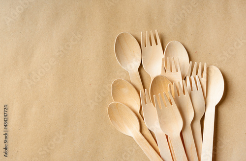 Disposable Wooden Cutlery Set on a paper background with copy space. Wooden forks, spoons and knives close-up. Wooden biodegradable table setting. photo