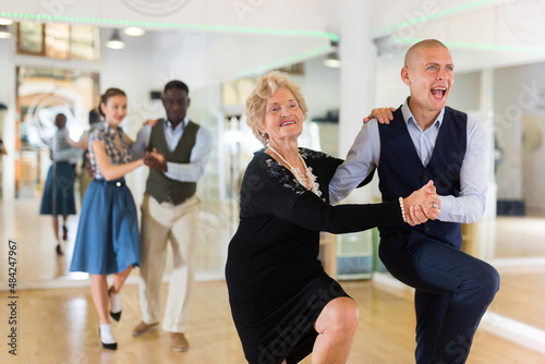 Mature woman learning to dance lindy hop with younger man 