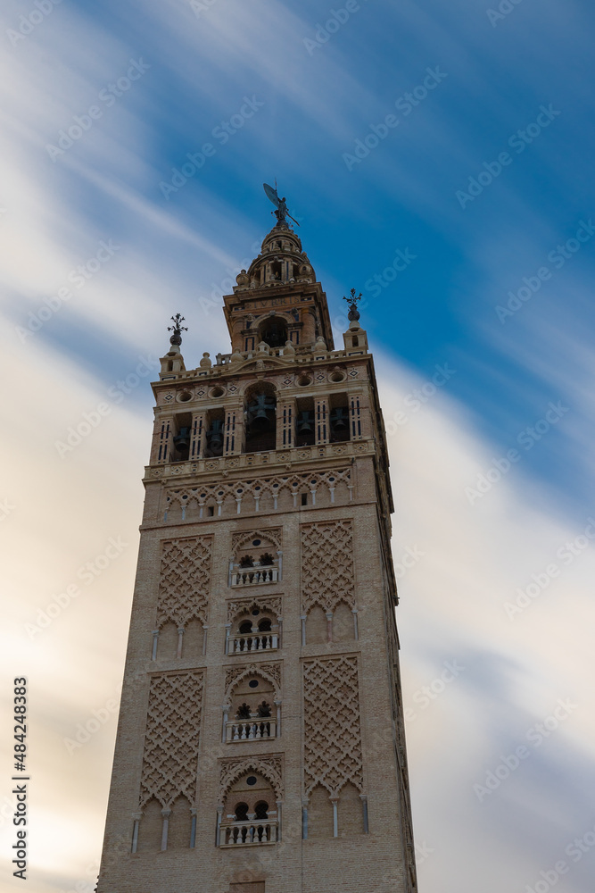A Long exposure during the day with a view on the historic La Giralda tower in the heart of Seville with moving clouds. This iconic landmark can be seen throughout the city