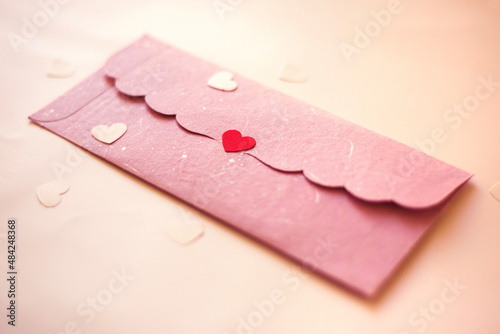 Pink color envelope sealed with red color heart shaped sticker. Valentines day object.