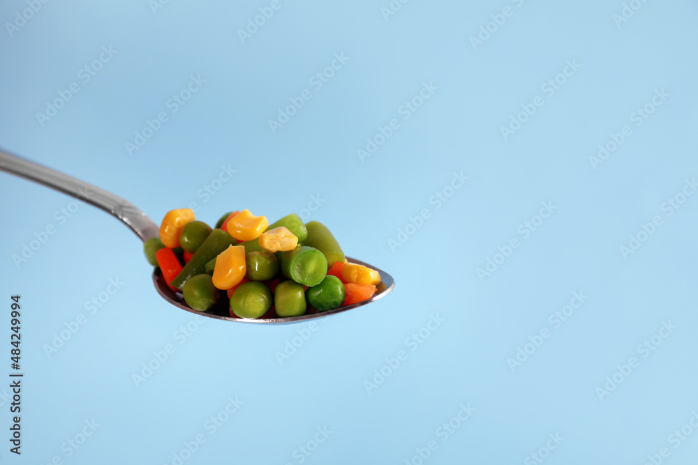 Fototapeta premium Fresh vegetables in spoon on light blue background. Space for text