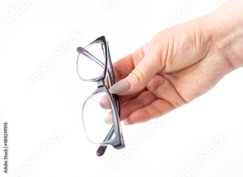 Glasses for vision correction in female hand on white photo