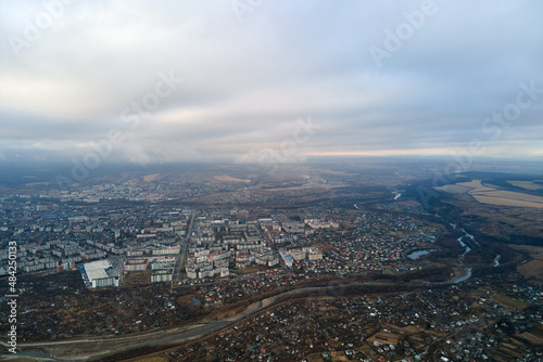 Aerial view of rural homes and distant high rise apartment buildings in city residential area during cloudy weather © bilanol