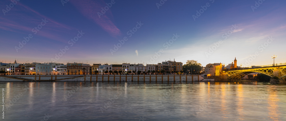 Sunset over the river Guadalquivir in downtown Seville with amazing colors in the sky and a view on the riverside of  the Triana neighbourhood.