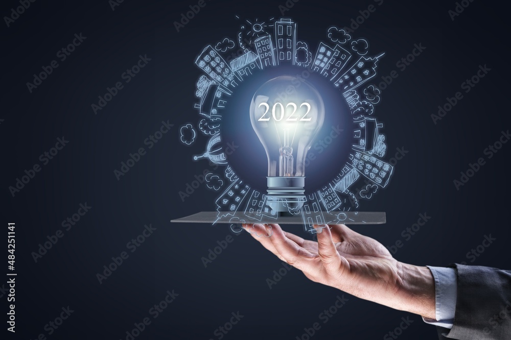 Concept of new year 2022 with new ideas in business. Hand hold a glass bulb Concept of new year 2022 with new ideas in business. Hand hold a glass bulb