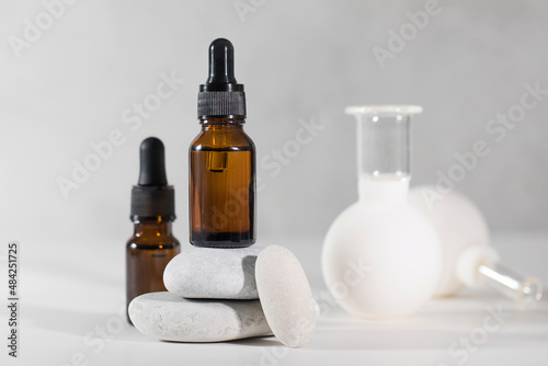 Brown droppers with cosmetics on a pedestal of stones and vacuum cupping massagers in the background.