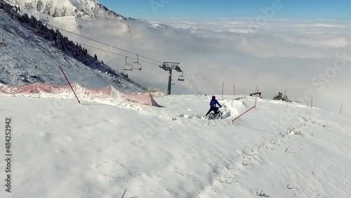 Aerial view above a man mountain biking in snow, drone shot. above the clouds