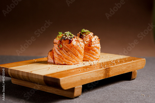 Salmon sushi freshly prepared. Japanese food, sushi roll of salmon in a wooden background. Fish and crustaceans slices. Front view with Copy Space. photo