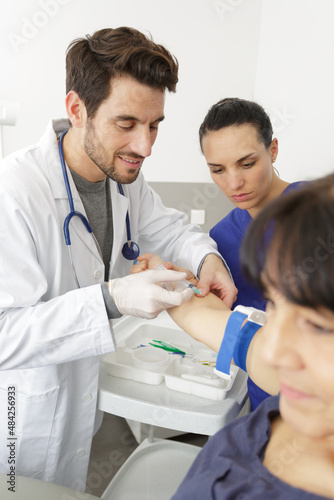 doctor doing a blood test on mature female patient