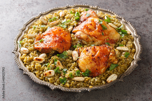 Plate of Traditional Syrian Freekeh with roasted chicken and almond closeup on the table. Horizontal photo