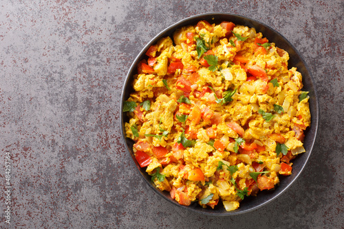 Classic Indian breakfast, egg Bhurji is a spicy mouth watering spin on scrambled eggs closeup in the plate on the table. Horizontal top view from above