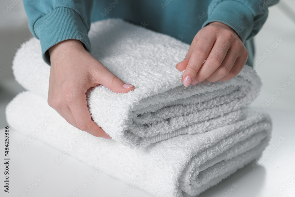 Woman touching soft white towel indoors, closeup Woman touching soft white towel indoors, closeup