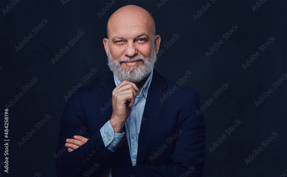 Glad and pensive old man posing against dark background Glad and pensive old man posing against dark background