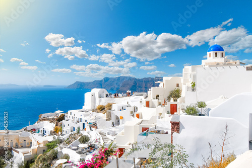 Fototapeta Naklejka Na Ścianę i Meble -  View from a whitewashed terrace of the caldera, sea and village of Oia, Santorini, Greece, with one of the famous blue dome churches in view.