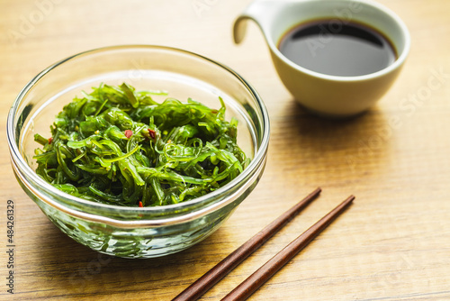 Green wakame. Seaweed salad and soy sauce in bowl.