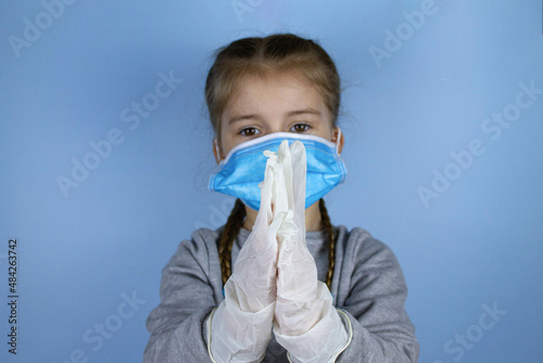 Little girl placing protective mask on face. Child against a pandemic, virus, infection Coronavirus, Covid-19 concept.