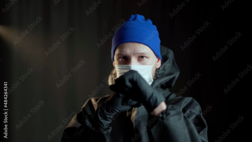 A man in a black medical suit of chemical protection and a white respirator and in black medical gloves and a blue hat delivers boxing punches A man in a black medical suit of chemical protection and a white respirator and in black medical gloves and a blue hat delivers boxing punches