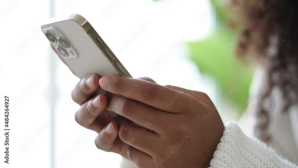 African American Girl using iPhone 12 smartphone pressing finger, reading social media internet, typing text or shopping online Mobile phone in two black hands 13.12.21 St.Petersburg Russia.