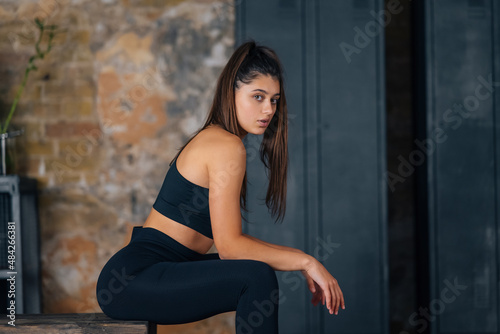 Sporty woman in sportswear resting on bench at fitness.