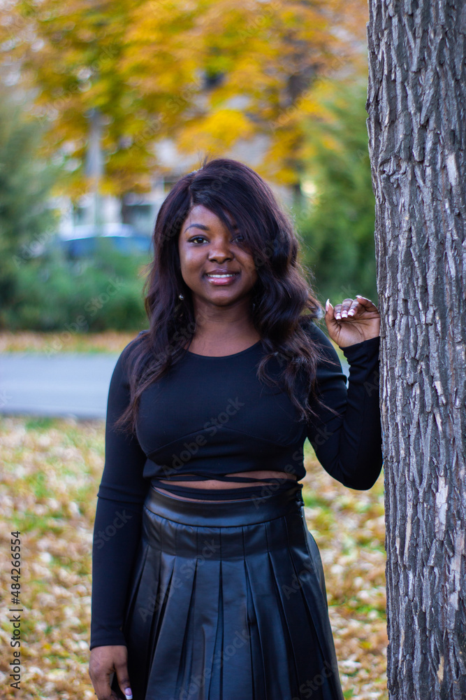 Front view of a beautiful African lady wearing a black dress in a park. Front view of a beautiful African lady wearing a black dress in a park.