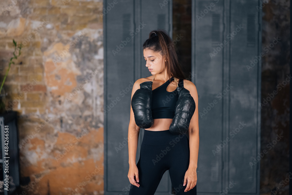 Fototapeta premium Sporty woman in sportswear posing on camera with boxing gloves.