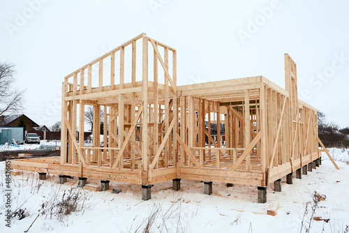 Wood frame house under construction, bare frame with pile foundation, winter season photo