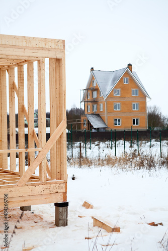 Wood frame house under construction against brick house at winter season photo