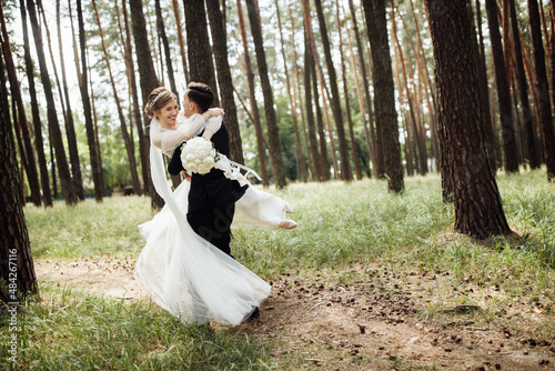 the groom hugs the bride. wedding day of a young couple. lovers walk in the forest