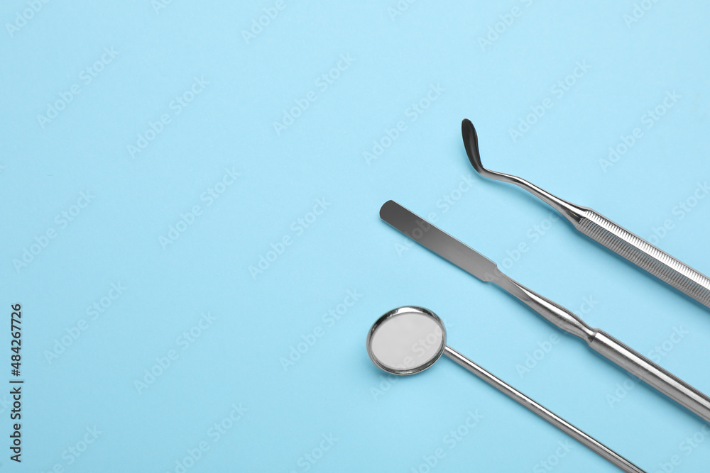 Set of different dentist's tools on light blue background, flat lay. Space for text Set of different dentist's tools on light blue background, flat lay. Space for text