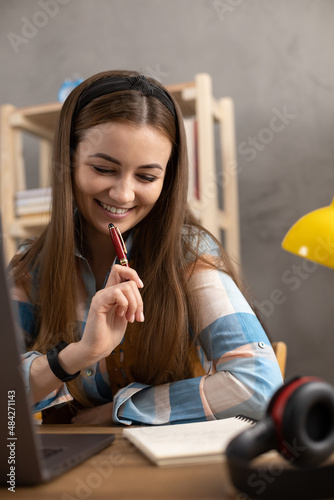 Girl writing in notebook noting thinking idea solitions. Student woman online larning photo