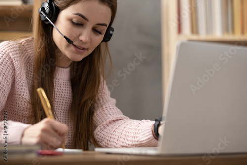 Girl writing in notebook noting thinking idea solitions. Student woman online larning