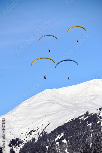 paragliding in the mountains over snowcapped mountains 