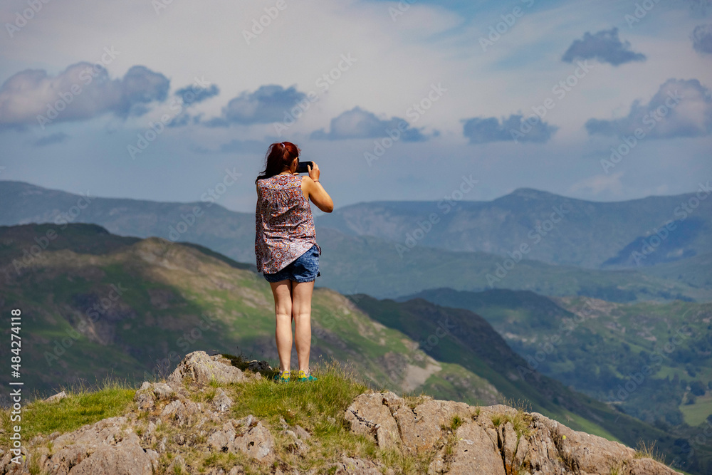 a lady standing on top of a mountain with the camera