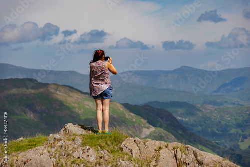 a lady standing on top of a mountain with the camera
