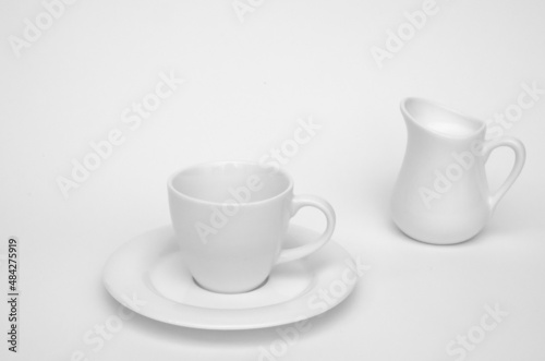 white coffee cup and milk jug with milk on white background