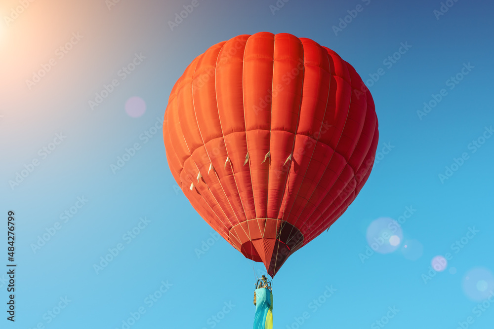 Fototapeta premium Red hot air balloon with the flag of Ukraine on a blue sky background