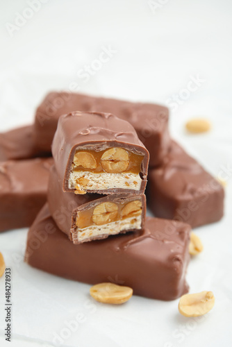 Chocolate bars with caramel, nuts and nougat on white table, closeup
