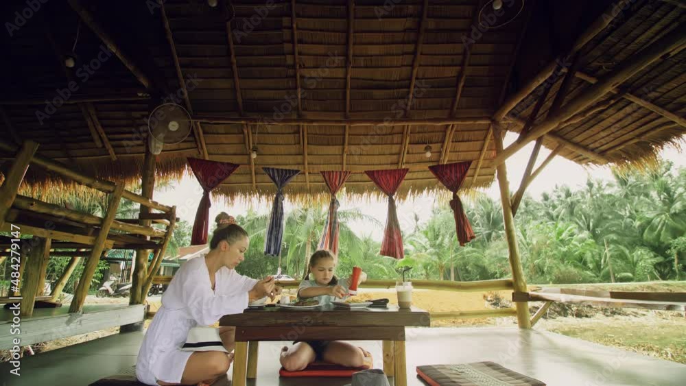The happy family eat and drink tasty beverages spending time in local floating cafe on water. Mother and daughter having breakfast outdoors. The happy family eat and drink tasty beverages spending time in local floating cafe on water. Mother and daughter having breakfast outdoors.