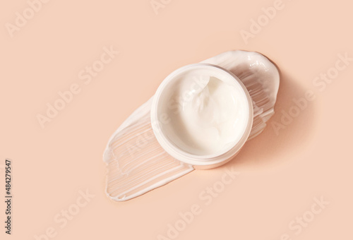 White smeared cream or cosmetic face mask with the open cosmetic jar.  Purifying and moisturizing cream. Flat lay