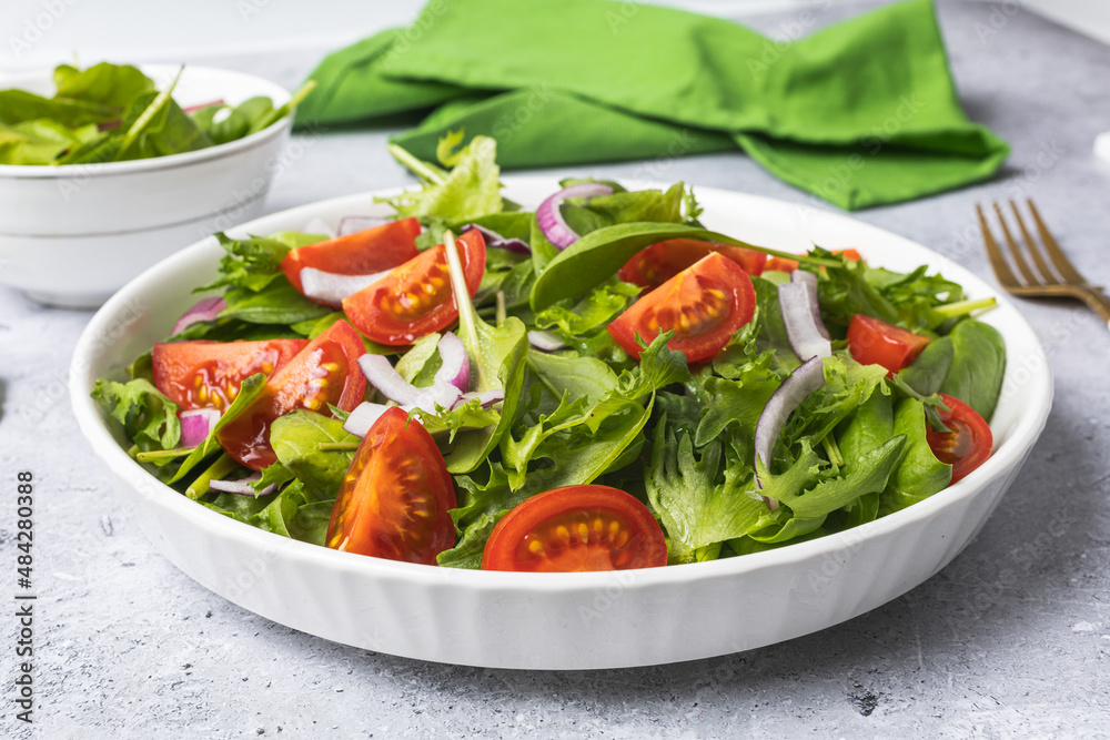 Summer green salad in white bowl plate on grey table Summer green salad in white bowl plate on grey table