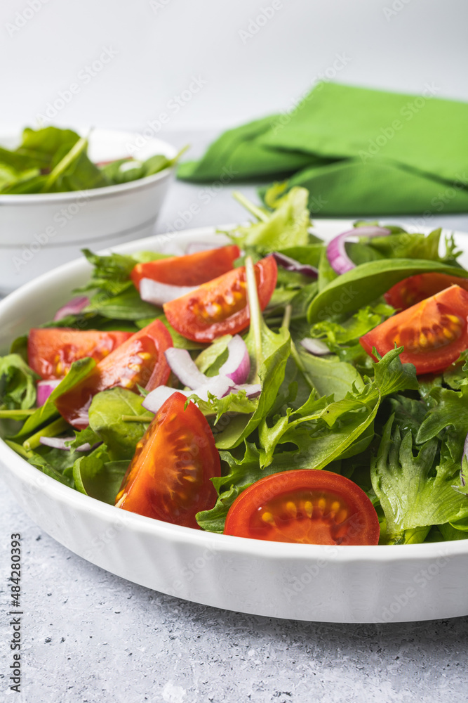 Summer green salad in white bowl plate on grey table Summer green salad in white bowl plate on grey table