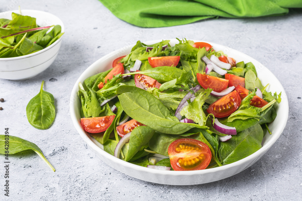 Summer green salad in white bowl plate on grey table Summer green salad in white bowl plate on grey table