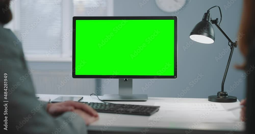 Over shoulder view of two business partners using pc with chroma key monitor during meeting at office. Focus on black green screen of computer. Over shoulder view of two business partners using pc with chroma key monitor during meeting at office. Focus on black green screen of computer.
