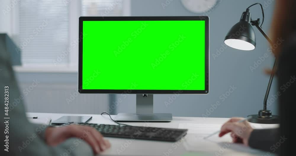 Caucasian business colleagues using modern pc with chroma key screen during conference at bright office. Back view of man and woman. Technology for work.