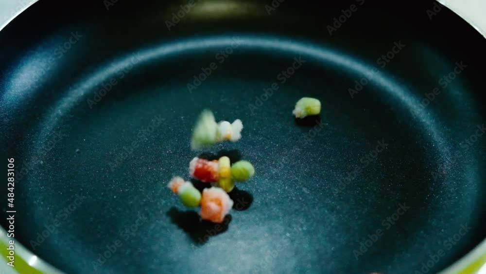 Frozen vegetables for frying fall into pan. Super slow motion. Cooking healthy food in home kitchen. Ecological lifestyle, healthy food preparation. Frozen vegetables for frying fall into pan. Super slow motion. Cooking healthy food in home kitchen. Ecological lifestyle, healthy food preparation.