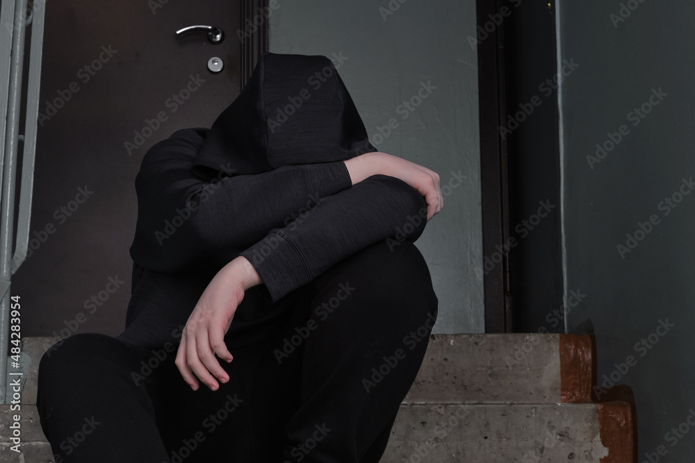 Depressed  teenage sitting alone after using drugs or alcohol over grunge concrete wall. Drugs addiction. The concept of the fight against drugs. International Day against Drug.