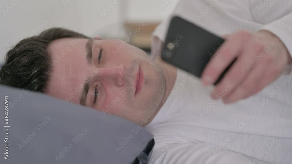 Man using Smartphone while Sleeping in Bed, Close up Man using Smartphone while Sleeping in Bed, Close up