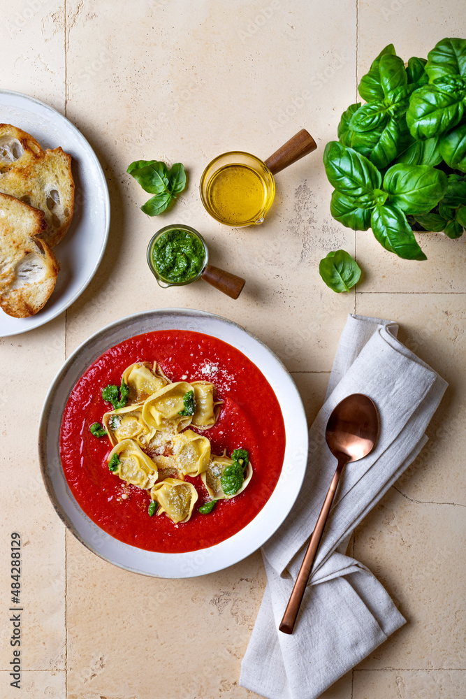 Homemade Italian tomato or roasted pepper soup with tortellini, pesto and parmesan cheese. Top view