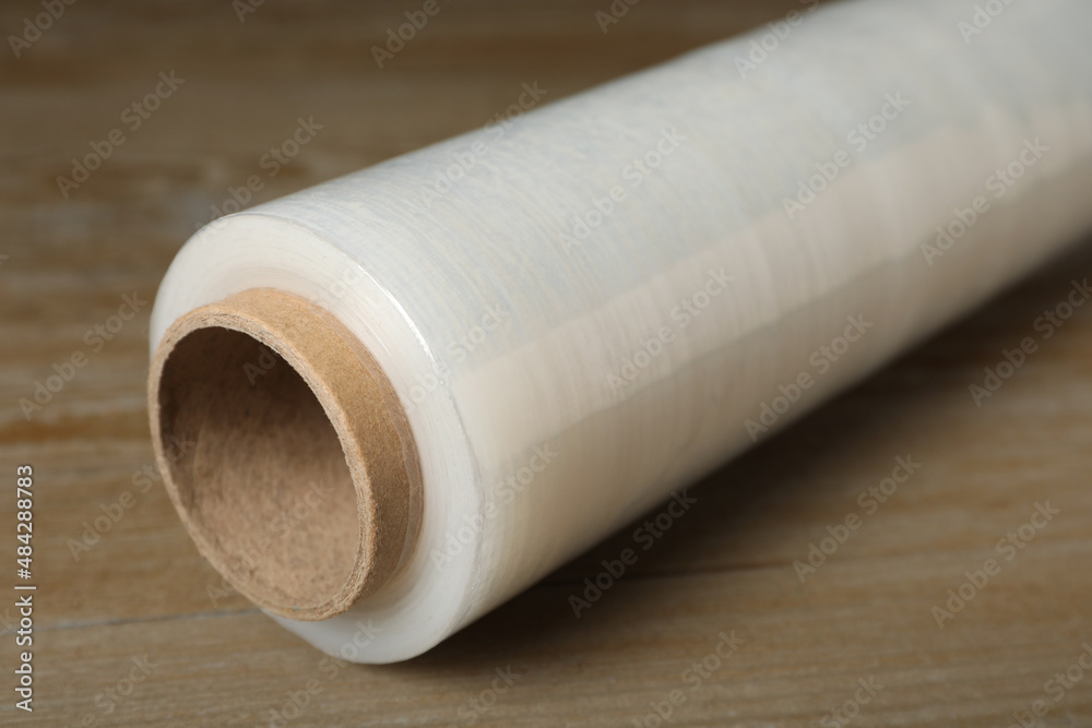 Roll of plastic stretch wrap film on wooden table, closeup Roll of plastic stretch wrap film on wooden table, closeup