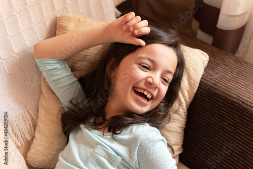 Girl laughing lying on the couch at home, Toledo, Spain photo